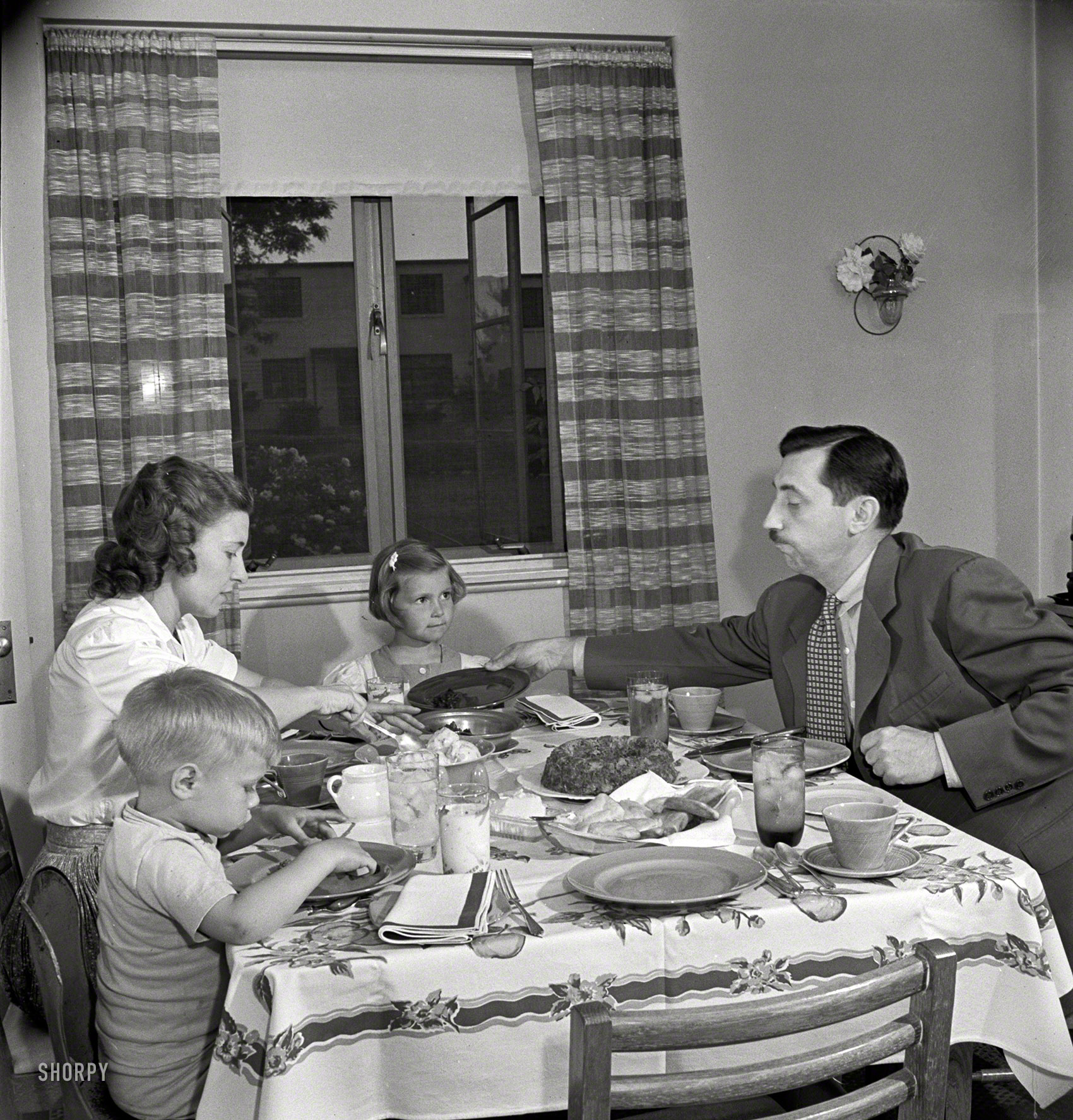 May 1942. Greenbelt, Maryland. Back at the Dream Kitchen table. "Federal housing project. Mr. and Mrs. Leslie Atkins, Ann, and Pierce Atkins having supper." Photo by Marjory Collins, Office of War Information. View full size.