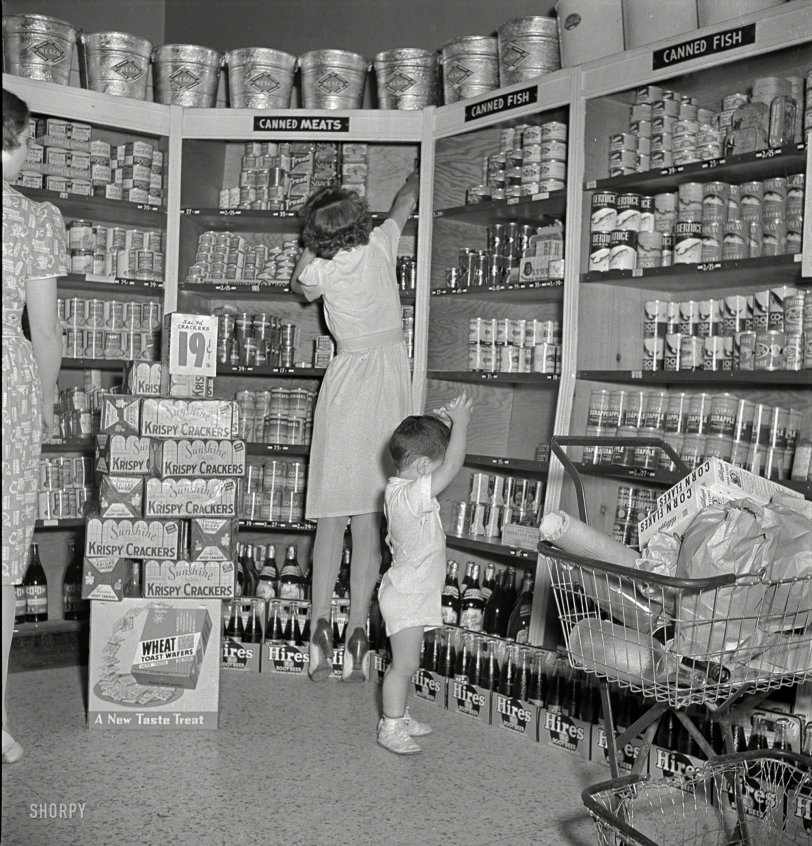 May 1942. "Greenbelt, Maryland. Federal housing project. Shopping in the cooperative grocery store." Hunting for that last can of Spam. Photo by Marjory Collins for the Resettlement Administration. View full size.
