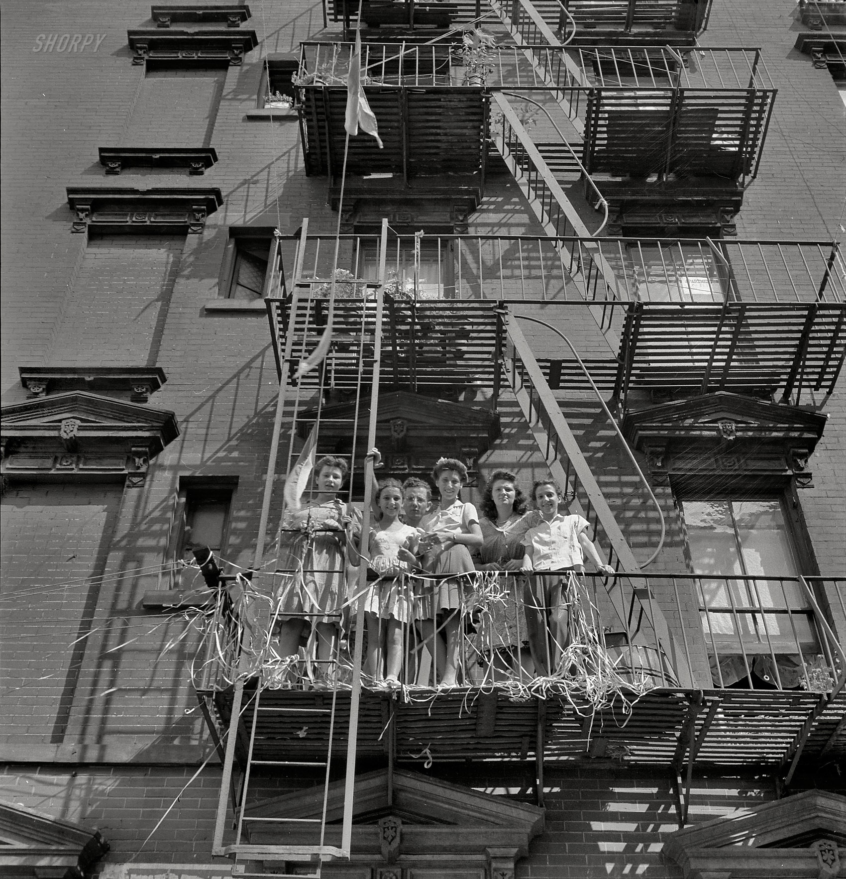New York, August 1942. "Italian girls watching parade on Mott Street and flag raising ceremony in honor of boys from the neighborhood in the U.S. Army." Photo by Marjory Collins for the Office of War Information. View full size.