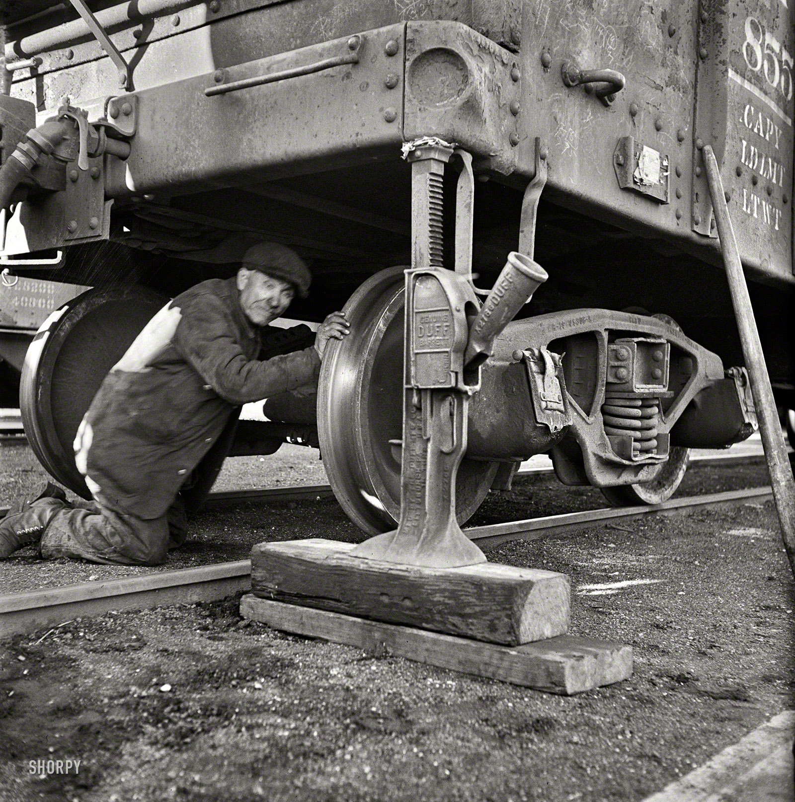 November 1942. "Chicago, Illinois. Jacking up a car on the repair tracks at an Illinois Central Railroad yard." Someone get the spare out of the trunk? Medium-format negative by Jack Delano, Office of War Information. View full size.