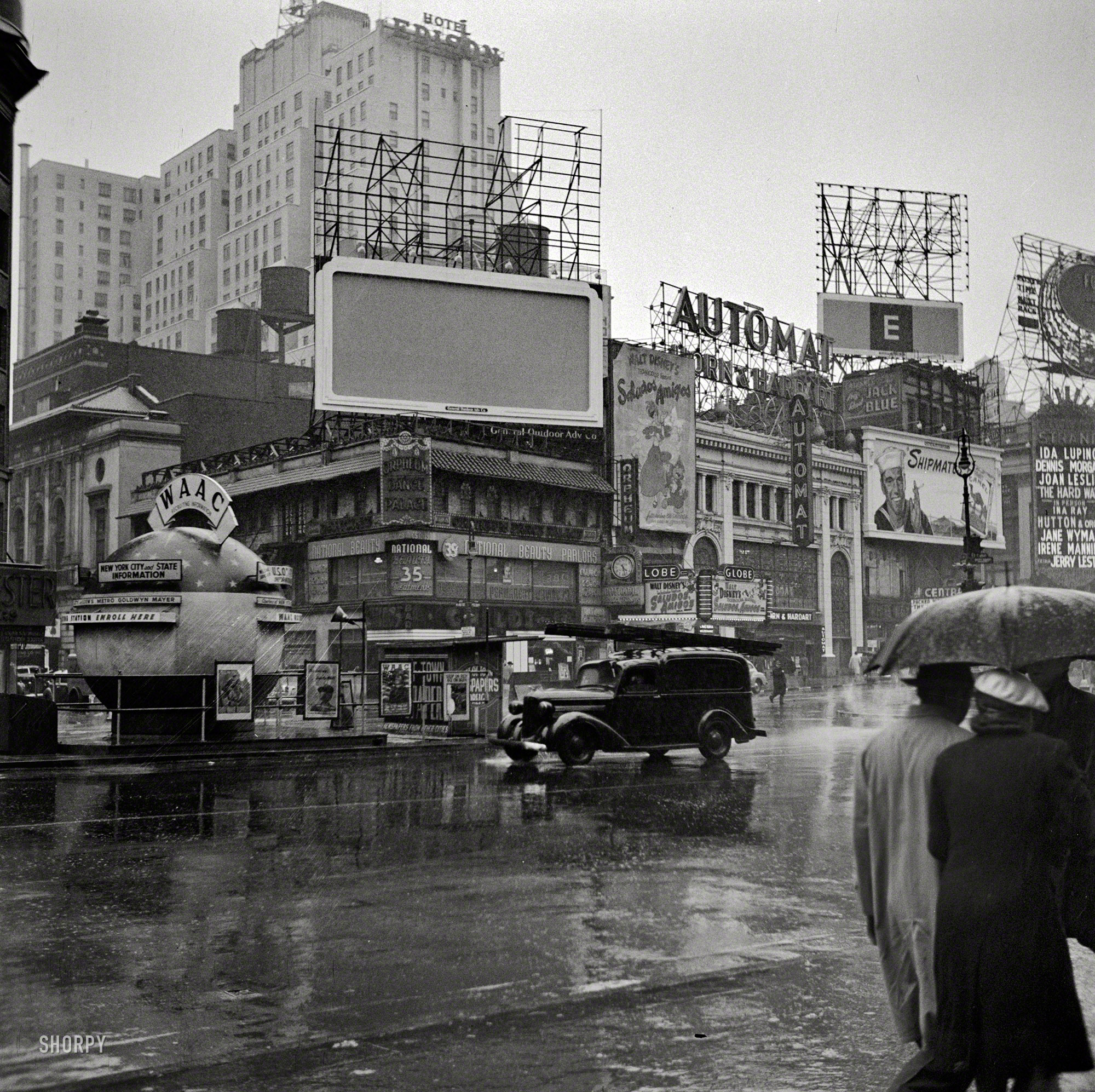 March 1943. "New York, N.Y. Times Square on a rainy day." Now playing: Disney's "Saludos Amigos." Afterward we can grab a bite at the Automat. Medium format negative by John Vachon, Office of War Information. View full size.