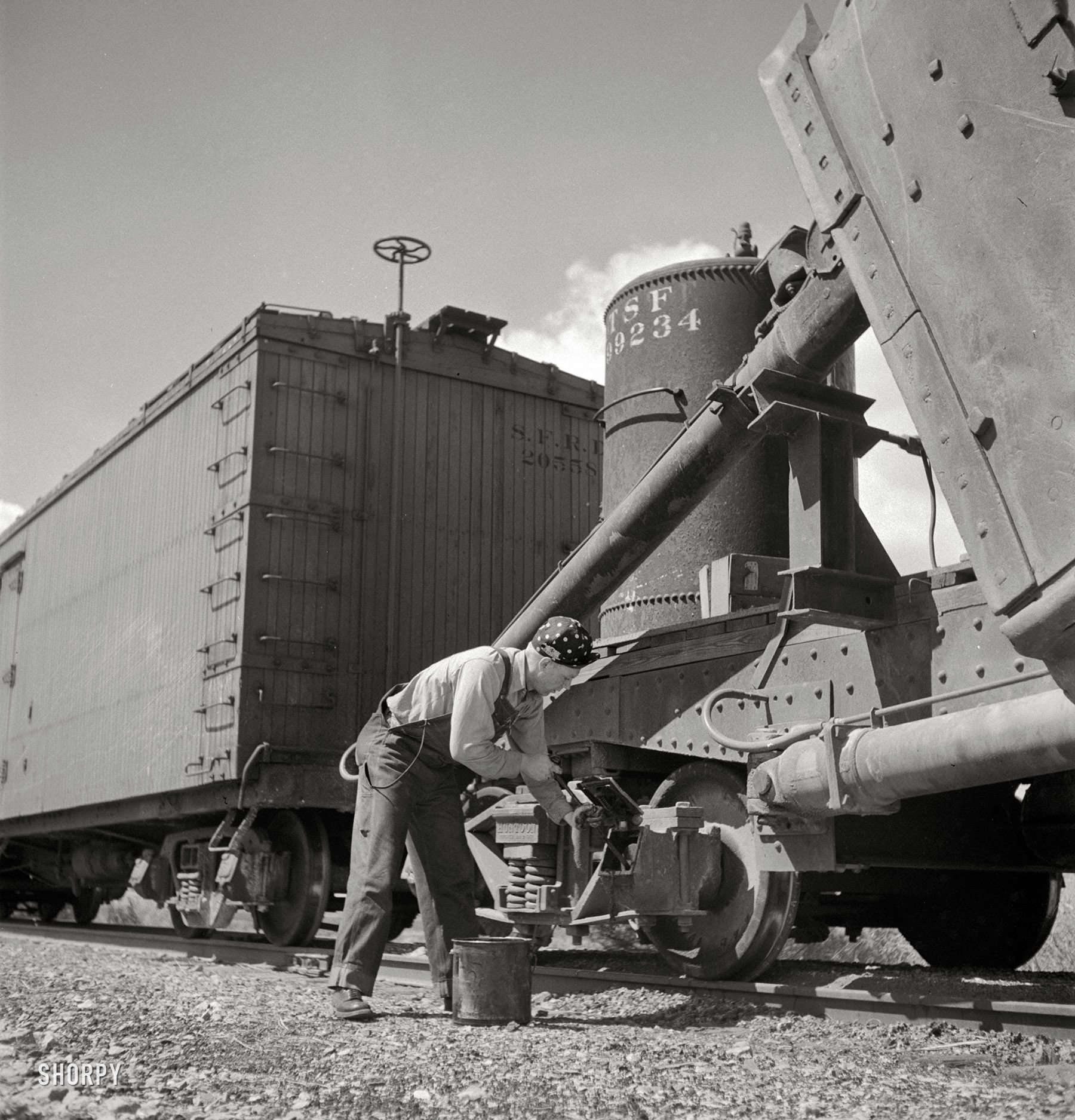 March 1943. "Acomita, New Mexico. Brakeman R.E. Capsey repacking a journal box of a special car as the train on the Atchison, Topeka & Santa Fe Railroad between Belen and Gallup, New Mexico, waits on a siding." Medium-format negative by Jack Delano for the Office of War Information. View full size.