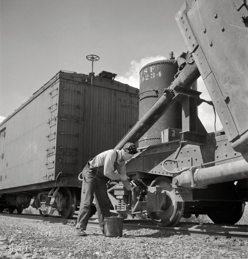 March 1943. "Acomita, New Mexico. Brakeman R.E. Capsey repacking a journal box of a special car as the train on the Atchison, Topeka &amp; Santa Fe Railroad between Belen and Gallup, New Mexico, waits on a siding." Medium-format negative by Jack Delano for the Office of War Information. View full size.
