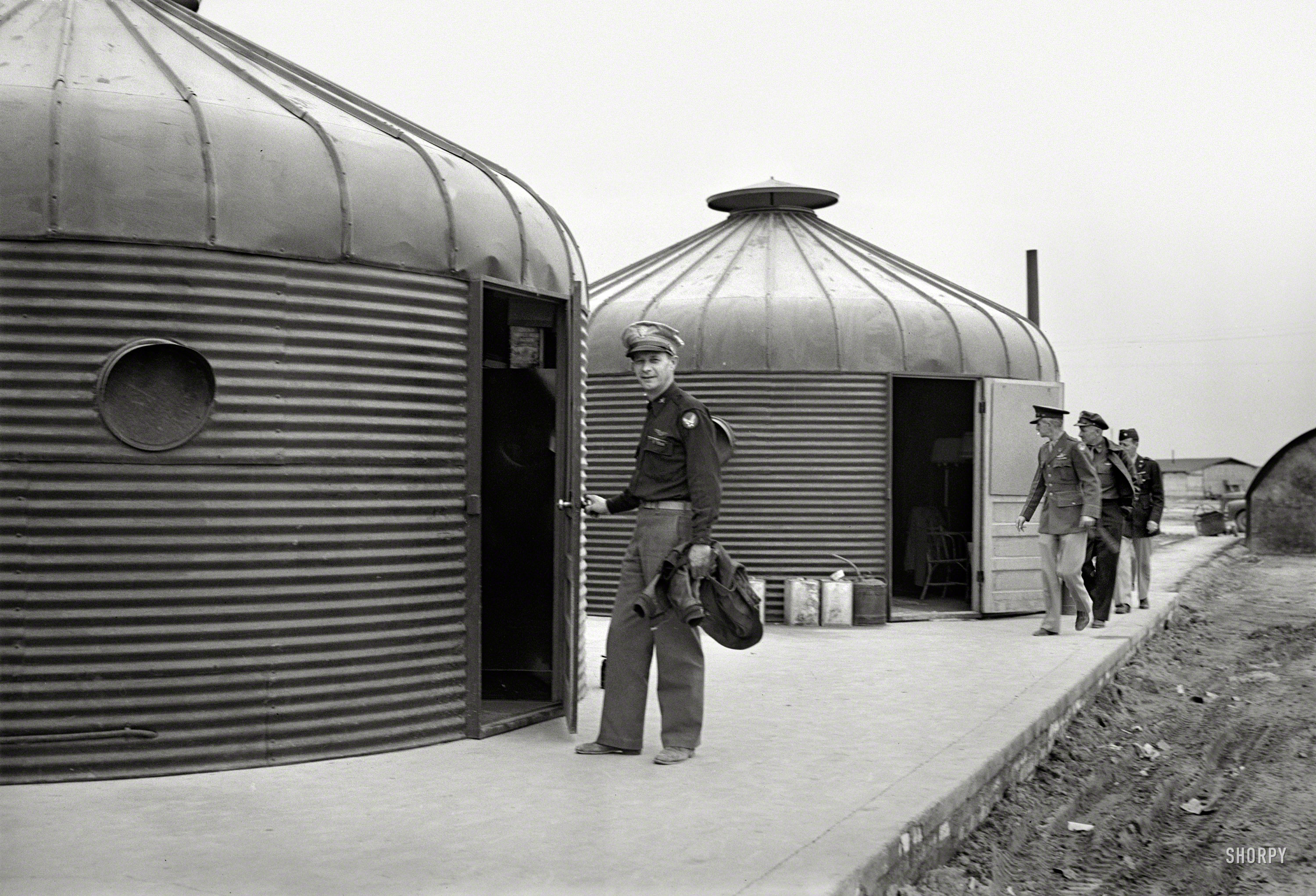 &nbsp; &nbsp; &nbsp; &nbsp; Somewhere in North Africa, with Carl Spaatz leading the group on the right.
Circa 1943, another look at the Dymaxion Deployment Units last seen here. In this view, corrugated steel with a glint of brass. Note the book (?) on the shelf. Office of War Information, photographer unknown. View full size.