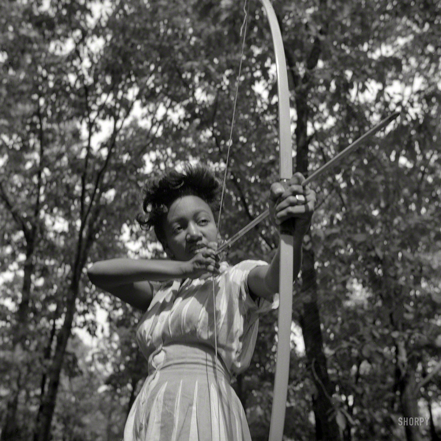 August 1943. "Bear Mountain, New York. Interracial activities at Camp Fern Rock, where children are aided by the Methodist Camp Service. Loretta Gyles of the Methodist Camp Service pulling a bow." Boys' Camp canoe at 11 o'clock! Photo by Gordon Parks for the Office of War Information. View full size.