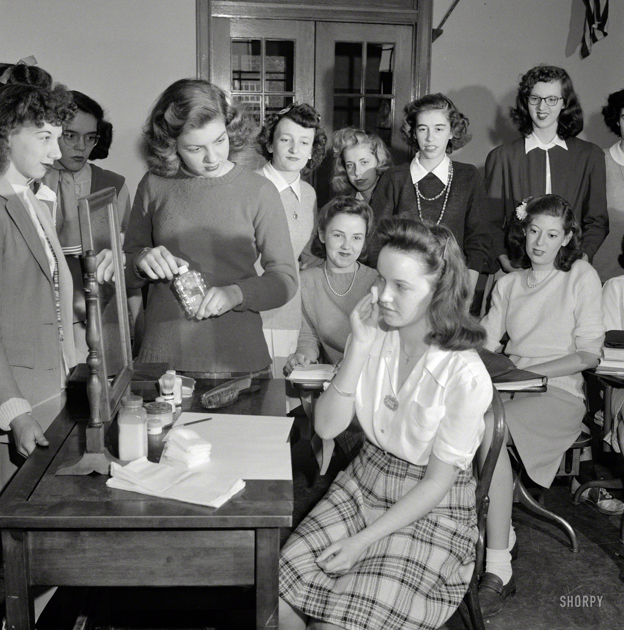 October 1943. Washington, D.C. "Demonstration of the correct procedure in applying street makeup. Home management class at Woodrow Wilson High School." Photo by Esther Bubley, Office of War Information. View full size.