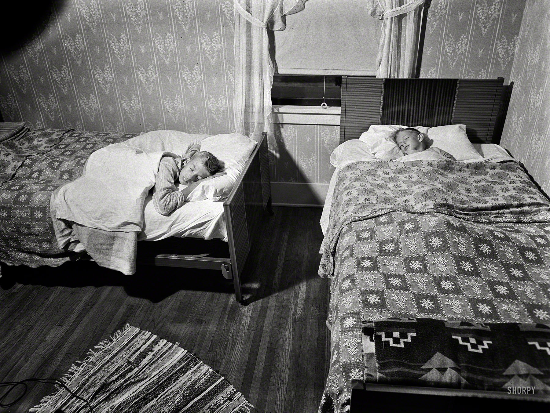 September 1942. "Rochester, New York. The two Babcock boys share one room." Howard and Earl drifting off to Slumberland, with Ralph Amdursky's floodight showing the way. Photo for the Office of War Information. View full size.