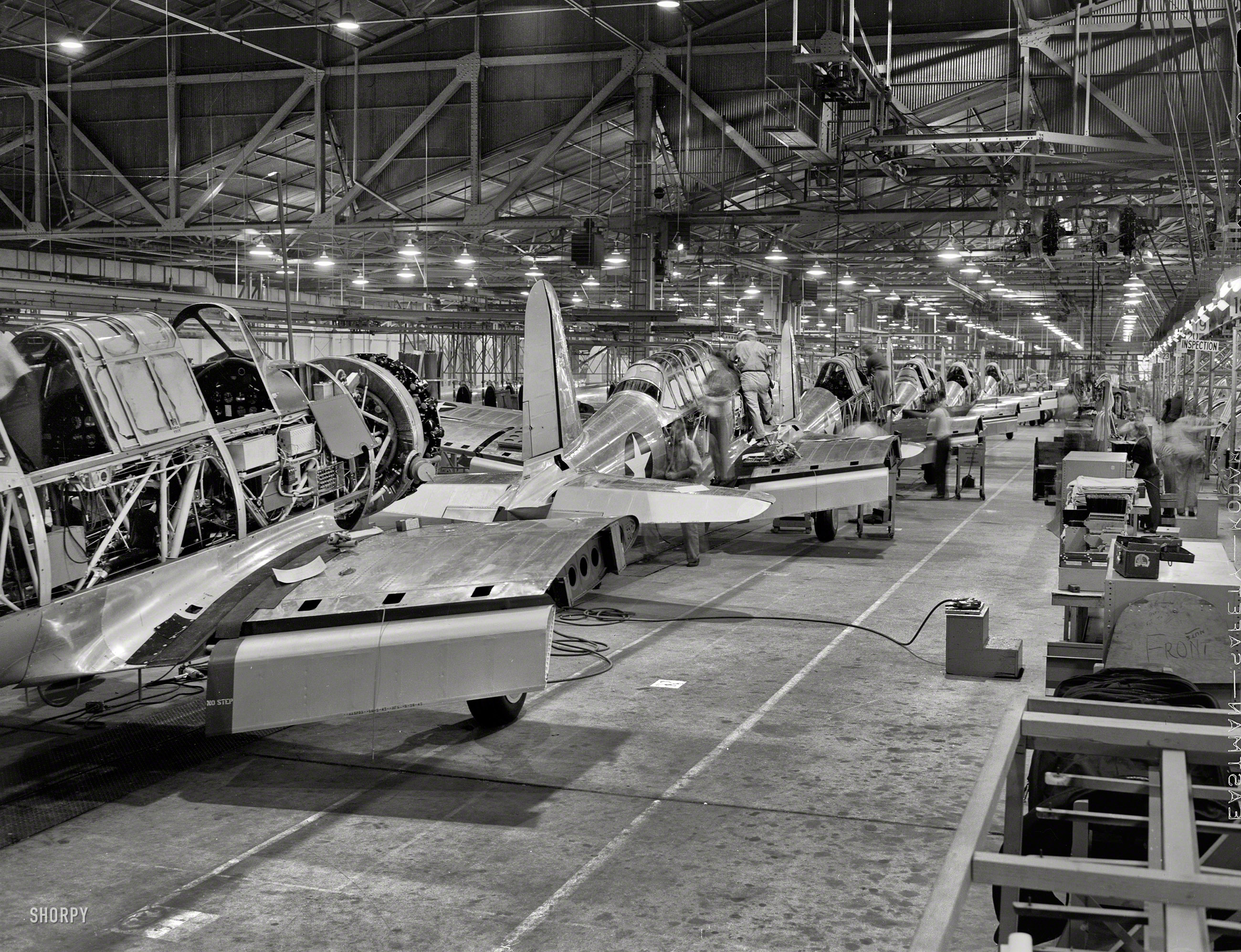 1942. "Final assembly at Vultee's Downey, California, plant of the BT-13A 'Valiant' basic trainer -- a fast, sturdy ship powered by a Pratt & Whitney Wasp engine." Photo by Alfred Palmer for the Office of War Information. View full size.