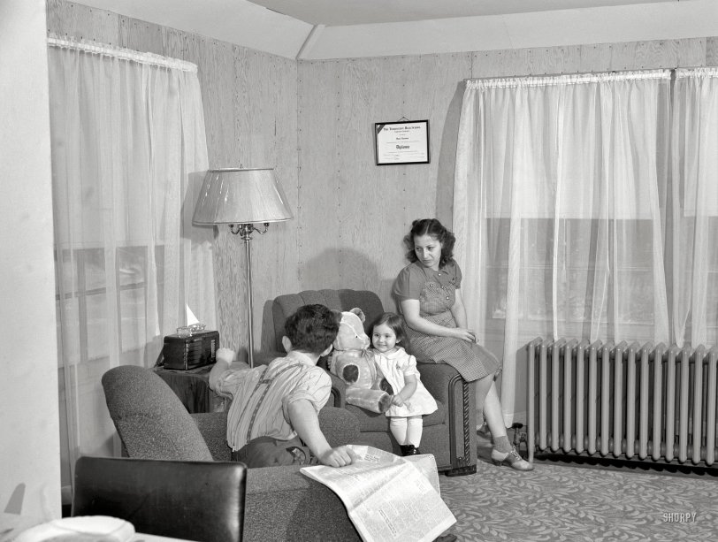 January 1942. Bantam, Connecticut. "Defense homes. Fred Heath works on the night shift at the Warren McArthur plant in Bantam, and spends his days with Mrs. Heath and their three-year-old daughter, Ann. Here they are in the living room of the Heaths' new four-room apartment, part of the new eighty-unit defense housing project just five minutes walk from the plant. The Heaths, who pay thirty dollars rent, like overstuffed chairs, and Ann also likes her overstuffed Teddy Bear." 4x5 nitrate negative by Howard Hollem. View full size.
