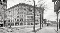 Binghamton, New York, circa 1905. "Kilmer factory." The wellspring of Dr. Kilmer's Swamp Root, a popular patent medicine. The building was also the temporary headquarters of another Kilmer enterprise, the Binghamton Press newspaper. Panorama of two 8x10 inch glass negatives. View full size.
Why?What exactly were these guards for around the tree trunks?  I've seen squirrels do amazing things and getting past those would be a cinch!
[Horses nibble. - Dave]
DetailsNo awnings above the second floor, sorry, folks. Interesting detail of brackets at the cornice line, how they line up with the wall below.  What's the picture of a building in the storefront, just to the left of the corner entrance. Nice looking building, wonder, is it still there? 
15 Herbal IngredientsDr. Kilmer blended 15 herbal ingredients for Swamp-Root: from South Africa, North and South America, Europe, the Middle East, Tibet, and North-west China, into a balanced formula that benefits the digestive, respiratory, and nervous systems.
Solidly BuiltLooks like Dr. Kilmer's building is still there, as is the Erie RR Station referred to on the sign:
Dr. Kilmer&#039;s Virginia EstateI grew up not too far from where Dr. Kilmer had an estate on the Rappahannock River in Virginia.  The name of the community that grew up around the farm where he trained his Kentucky Derby horses is called Remlik, which is, of course, Kilmer spelled backward.  The area is still called Remlik and until recently there was a Remlik post office.
Yup, still thereDeeGee, yes, the Kilmer Building is still there. It houses a bar &amp; grill called Remliks, among other things. The railroad station is there too, but no longer functions as a station - bunch of different businesses in and out of the space - I think it's a hairdresser right now? Not sure. Just down the street is the AAA ball field, home of the Binghamton Mets.
(Panoramas, DPC, Railroads)