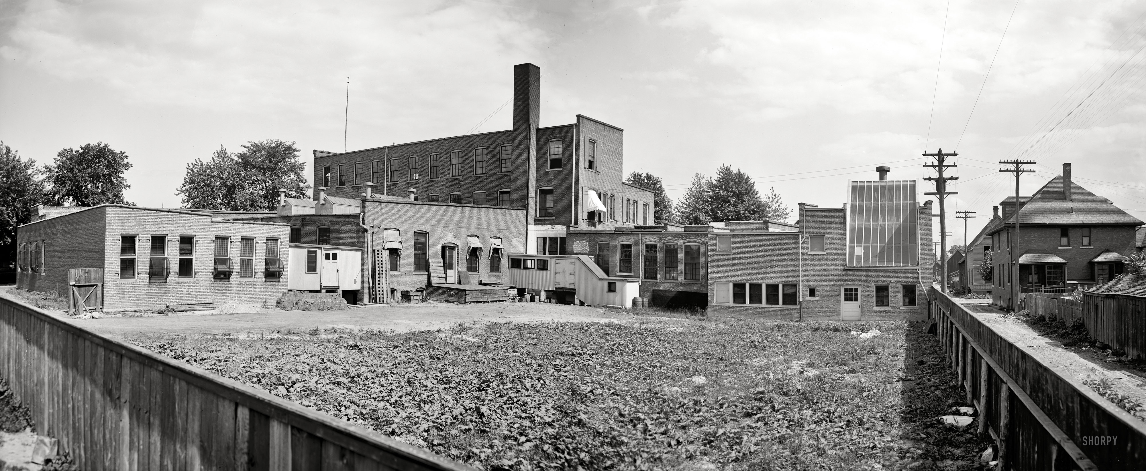 Detroit circa 1906. "Detroit Publishing Co., northwest view." Note the greenhouse-style glass to the right employing sunlight for printing and perhaps enlargement, as well as the unusual windows to the left. In the early years of the 20th century, the company was one of the world's biggest producers of color postcards. Panorama made from two 8x10 inch glass negatives. View full size.