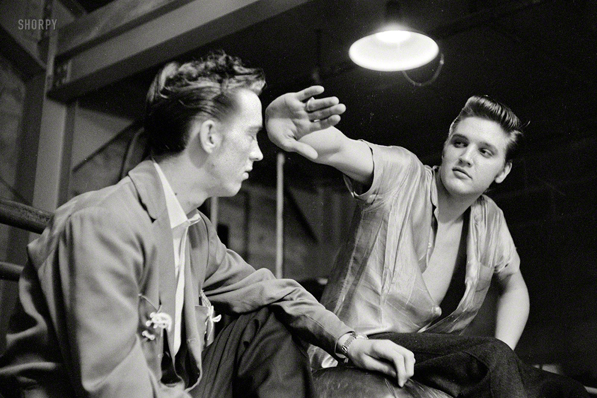 May 27, 1956. Dayton, Ohio. A 21-year-old Elvis Presley with his cousin Gene Smith backstage at the University of Dayton field house, where they sang for a zillion swooning coeds. 35mm negative by Phillip Harrington. View full size.