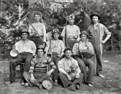 New Zealand circa 1905. "Eight young men in ragtag clothing with hats, pots, broom, shovel, accordion, pipes, gun and dog. Sumner, Christchurch." Five of these fun-loving hayseeds are the Myrtle Campers from this post. Glass negative by Adam Maclay, Alexander Turnbull Library. View full size.
Belt Buckles 2Those are British Enfield Snake buckles. It's an old military design and had been around a long time by the time of this photo. Those buckles were common imports to both the Confederate and Union Army during the Civil War. 
Handsome rakesThe one in the stripes has me mesmerized and some of the others aren't bad, either.  I love these New Zealand photos.  Are there any that show the Maori?
Belt bucklesInteresting belt "buckles". At least four of them have the same style. Anything to this? 
The Rifleis a Flobert, a popular, inexpensive gun made in Belgium. At one time, "Flobert" was a generic term for "beginner" rifles.
(The Gallery, Adam Maclay, Dogs, New Zealand)