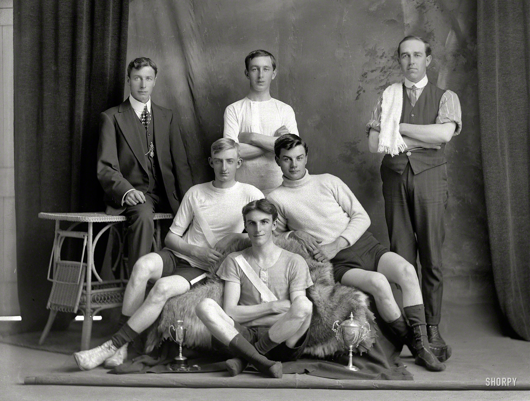 New Zealand circa 1910. "Studio portrait of bicycle road racing team with four young men in riding attire with two small cups, manager with polka dot tie and coach alongside, Christchurch." Glass negative by Adam Maclay. View full size.