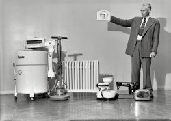 Wellington, New Zealand, circa 1950. "Household appliances including washing &amp; sewing machine, mixer, toaster, polisher and heater." Also a control-robot with three hands -- hour, minute and left. Photo by K.E. Niven &amp; Co. View full size.
For want of a nailWe could have hung the clock on the wall right about here.
Can we get a close-up on the plugs?It would help solve the raging controversy of Princess Unplugged.
Edit: Thanks!  Hmm.  Looks like it could be the current (ha) standard Australia/New Zealand plug, but it could also be a US-standard plug with U-shaped ground (earth) pin.
(Kitchens etc., New Zealand)