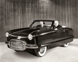 "1950 Nash experimental NXI." The Nash Experimental International, basis for the Nash Metropolitan, piloted by Nash-Kelvinator Chairman George Mason with VP George Romney (Mitt's dad) riding shotgun. View full size.
Mini-CarOdd little beast, now slightly sought after 'special interest' car.  Had an engine sourced from MG, I believe. Worked for a fella that had one way back in the 60s.  He loved it, I couldn't understand why.
Another Matter of ScaleIn the mid 60's, my best friend and I (both 6 feet 4 inches tall) were hitchhiking to a shopping mall for some fun.  Coming down the road, we spotted a red &amp; white Metropolitan with its top down. I commented that wouldn't that be funny if he stopped to pick us up - which he promptly did.  The driver was nearly the same size as us and my best friend protested about not being able to fit us all in.  The driver insisted so my friend entered first, scooted over and I was looking at about 6 inches of seat to sit down on. When I said that I didn't think it was possible, the driver said, "No problem.  We can all squeeze in.  Just get in."  I sat down and pushed everyone together barely getting both feet inside and barely sitting on the seat.  The real problem was that because there was not enough room to fully get in, my right knee was still sticking outside of the car with no where to go.  I tried to close the door, but my knee prevented it from closing or latching.  When I started to protest again, the driver said to just pull hard on the door and it would close.  So I followed his instructions and yanked on the door.  As the door closed, it pushed hard on my leg, driving it forward which eventually forced my right foot completely through the floorboard!  My foot was now sitting on the top of front tire.  I yelled for him to not move and told him what happened.  He said, "Ah, just hold your leg up away from the tire so we can get going".  And that is exactly what I did.  For the next five miles we drove merrily down the road with me looking at the tire spinning below and the driver telling us what a great car his Metropolitan was and how much he loved it.  My friend never said a word until we were both out of the car and it was on its way down the road at which point we both began a long laughing spell.  True Story!
Golden OldieReminds me of that song lyric "Beep beep, beep beep. His horn went beep-beep-beep!"
Caveman&#039;s PhotoshopLooks like a bit of stenciled burn/dodge in the old darkroom as evidenced by the line around the car / executives' heads where it meets the curtain. The effect is that the subject "pops" off the underexposed (on the print mind you) back / foreground.
[Your "stenciled burn/dodge" would have been achieved by scraping away the emulsion on the negative, or using an ink pen on a print. - Dave]
Well George,it looks like we've got the ribbon for the goofiest looking car design for 1950.
Grass KillerMy father had some kind of Nash when I was about 5 yrs. I'm 58 now. I quickly realized at this early age what Nash autos were good for....... killing grass. He'd move it in the yard occasionally and it would kill more grass. I think he had the clunker for several years before giving up on fixing it and selling it for parts. Transmission problem  best I remember.
... and it didn&#039;t hurt me noneThe Metropolitan's back seat wasn't really much of one.  Its bottom served as a battery cover and its back folded down for access to the trunk, which didn't have an external lid.
That said, my mother often tells me that, when I was an infant, she carried me around in a girlfriend's Metro by wedging my bassinet behind the front seat backs and atop the rear bench.  To my knowledge I was never ejected from the bassinet.  However, I suggest that Shorpyites take any of my posts with a grain of salt given that I was transported in that manner.
Ahead Of Its TimeSomehow, so strangely familiar.
Its just grandUnveiled on January 4th 1950 at the Waldorf-Astoria in NYC, the NXI was priced at under $1000, more here.
Kelvinator on wheelsStand this car on end and you'd think you might find a cold beer inside if you could find the big chrome handle.
Class wheelsAwesome roadster. Reminds me of the Sunbeam Tiger made famous in the 60's spy spoof Get Smart.
SimilarWas George the inspiration for that body styling?  They say people look like their pets, George bears more than a passing resemblance to his car.
[It was designed by William Flajole. - tterrace]
A Matter of ScaleThis antecedent of the Nash (and Hudson, briefly) Metropolitan looks even smaller with someone of Mason's impressive bulk wedged into the driver's seat.
Cost SavingsTo keep costs down there was no external trucklid.  Therefore, access to the trunk was via a flip down panel behind the rear seat.  There also was no glass side windows, but there were plastic side curtains.  The front bumper incorporated the grille.  The back bumper was the same piece, but without the grille.  The spare tire was then able to slide into the opening below the trunk.
There were many design changes made before the Metropolitan was introduced in March 1954.  The series of prototypes were called NKI for Nash Kelvinator International, and the NKI name almost made it into production.  The early press photos and service literature actually shows NKI instead of Metropolitan.
The December 2012 issue of Hemmings Classic Car has a four page story on the NXI/NKI/Metropolitan.  Note the spare tire behind the license plate in the photo below.
Lois Lane&#039;s car"Somehow, so strangely familiar."
Postwar NashGreat photo collection of postwar Nashes.  They had some pretty sporty concept cars. I got to shake Michigan's Governor George Romney's hand when he did a walk-through a Sears store were I was working in the stock room in my early college days.
Not Lois&#039; RideYour friendly "old car know it all guy" is back! Lois Lane's car in the 50s TV show was a 1950 Nash Rambler Convertible Coupe. Among other things, it was quite a bit larger than the later Metropolitan.
(The Gallery, Cars, Trucks, Buses)