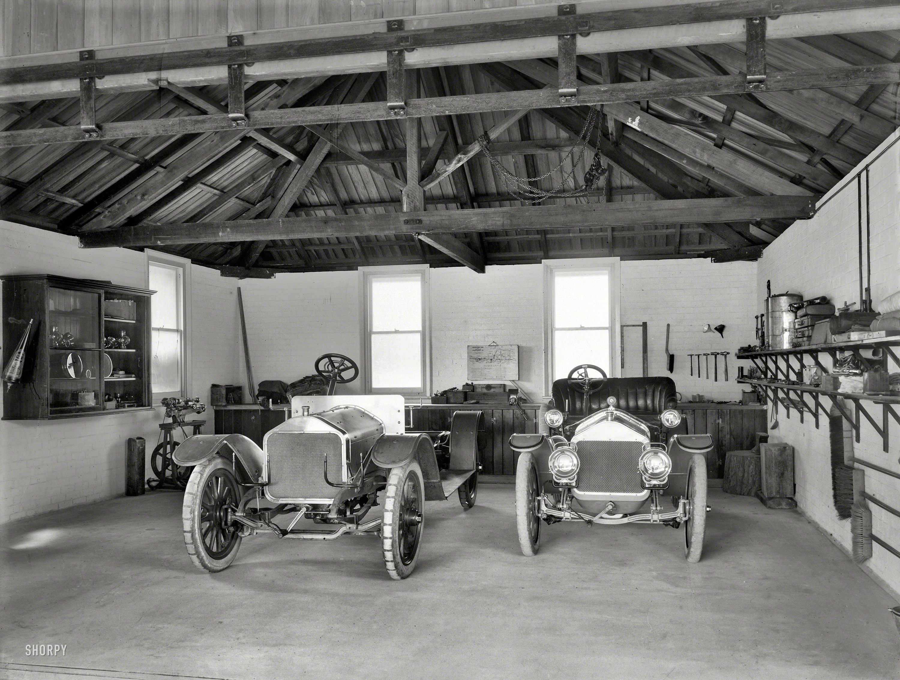 Christchurch, New Zealand, circa 1908. "Wolseley and Cadillac motor cars in garage." Glass plate by the Steffano Webb Photographic Studio. View full size.