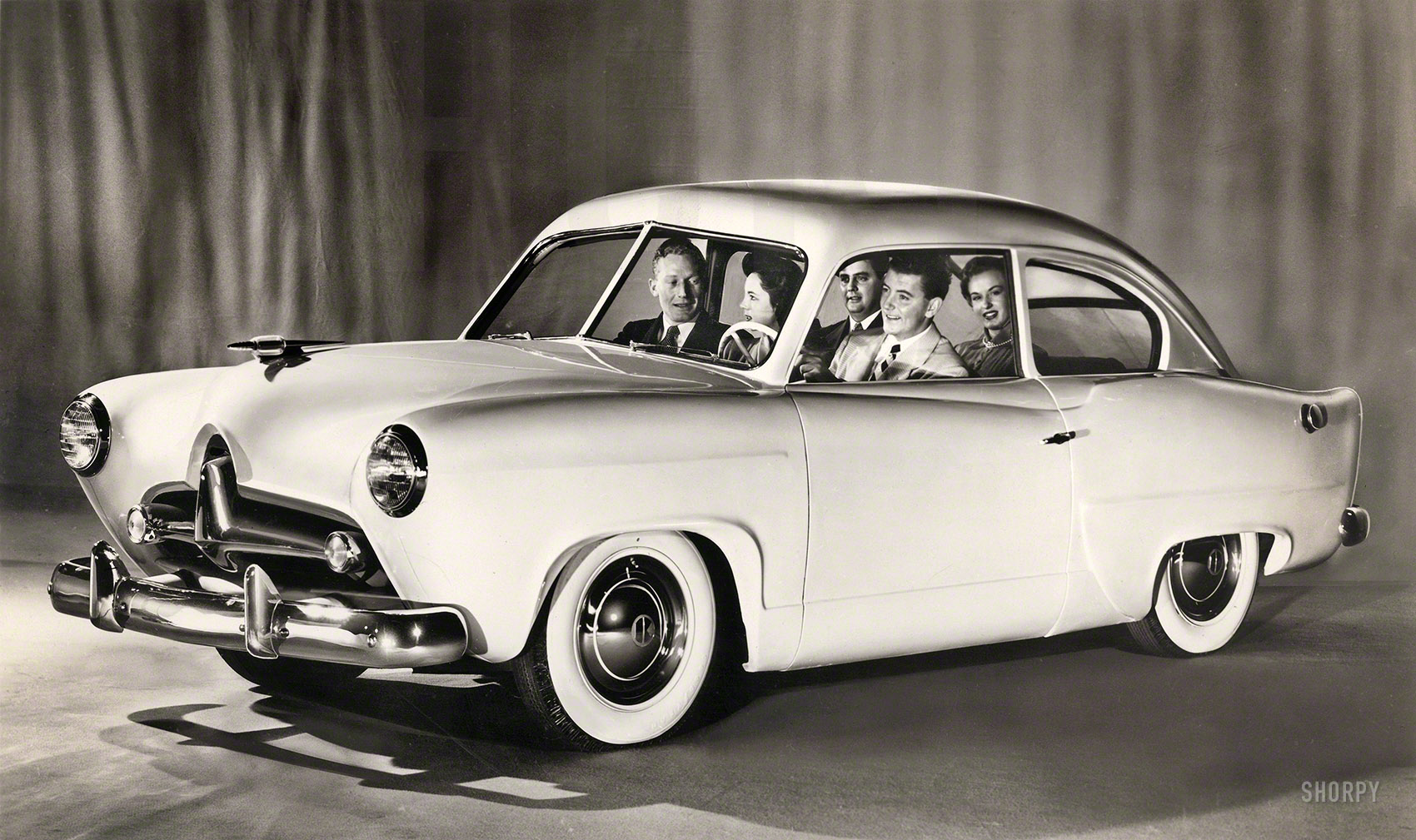 Publicity photo from late 1950 for the Kaiser "Henry J," a small car (named after company chairman Henry J. Kaiser) that was a few years ahead of its time. By 1954, the Henry J had tootled off into oblivion. View full size.