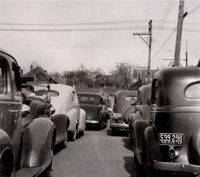 Eight 1930's cars sit in traffic. The closest one to the camera has a 1940 Indiana plate. I was able to determine that the plate on the car earlier in the line was 561 653 but not what state it was from. The photo came from an album found at a second hand store in Lancaster, California. View full size.
