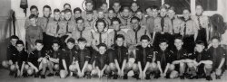 My sister, brother and me (11 years old), in a group photograph taken in 1957 of the St. Willibrord Scouting Group. We lived in Beek en Donk, a village in the Netherlands, 15 miles from Eindhoven, the home city of Philips Electronic Industries.
The group had been installed recently, my sister (18) was a leader at the Cub Scout group (called Bagheera), my older brother (14) was at that moment the oldest member of the Boy Scout group (leader of the Eagle patrol), and I was the youngest one (member of the Hawk patrol). At our first camp, I remember I was so cold my brother took me with him in his sleeping bag to warm me.
Note the hats and sticks that belonged to our outfit in the far right corner. The campaign hat was said to be so practical: It protected you against rain and sun, and it could be used to stoke up a fire. The stick could be used to carry heavy loads (like filled water bags), or scare enemies with it (like snakes or wild animals). View full size.
(ShorpyBlog, Member Gallery)