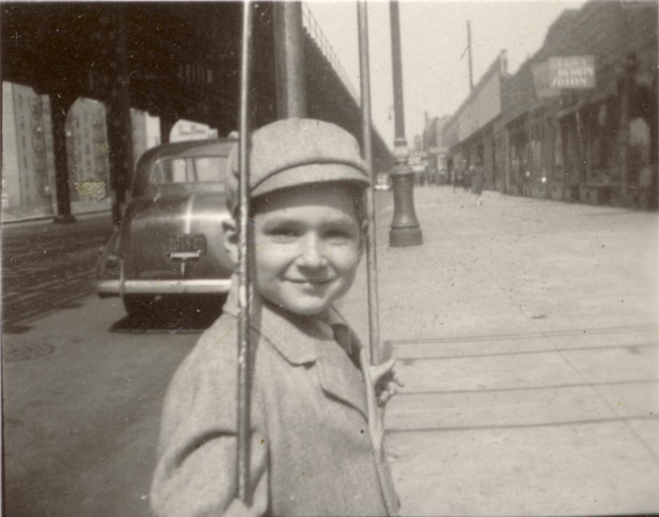 This is a photograph of me in front of my grandfather's bar, the Half Moon Inn. It was located on White Plains Road between Maran Place and Lydig Avenue, Bronx, NY. The bars are holding up a canopy in front of the Half Moon Inn. The camera is facing north, and the elevated railroad, on the left, runs above White Plains Road. 