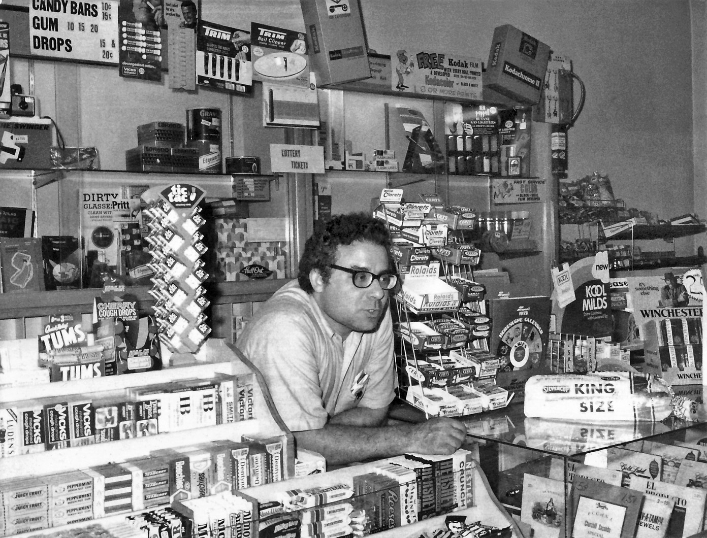 This picture is of my dad, Bernard "Bernie" Falk, taken at the candy counter of the luncheonette he and my Mom owned in 1973. Thel-Bern Sweet Shoppe, Main Ave., Passaic NJ. Dad would sell the store in 1977 and move onto to the glamorous world of  'The Coin Business.' I think my brother took this photo with a Polaroid Swinger like the one in the box in the display case top left. View full size.
