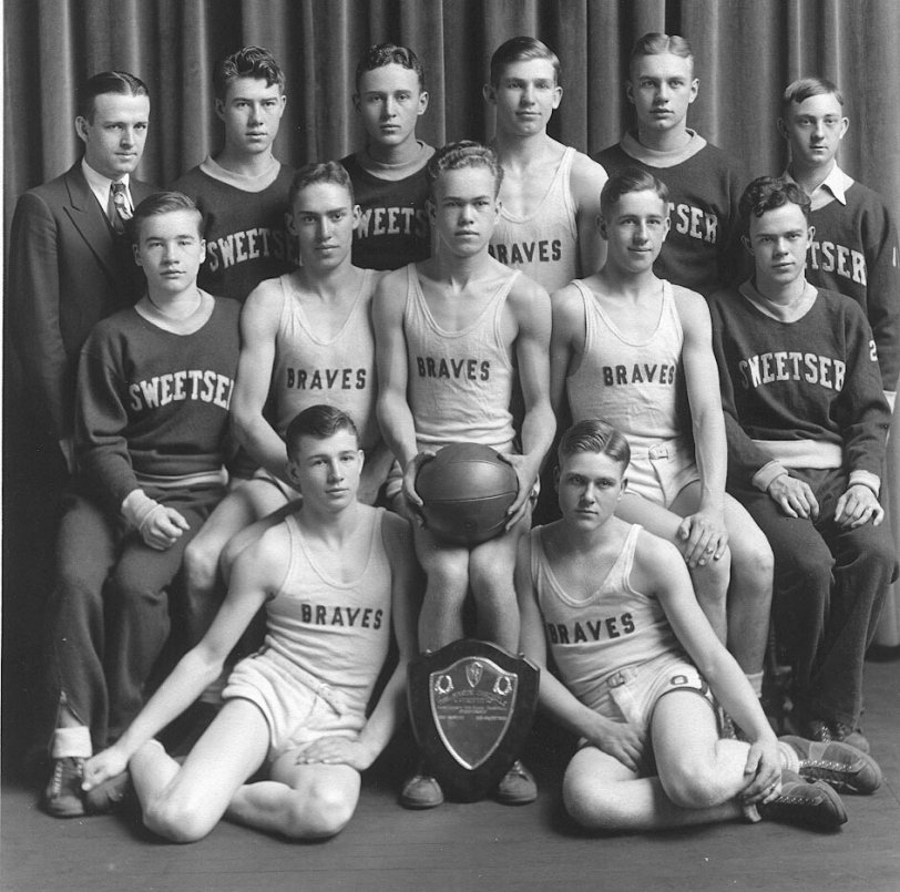 This is the 1932 basketball team of the Sweetser Braves. Sweetser is a small town in Grant County Indiana. This photo celebrates the team's win of the Grant County Championship. The win is significant because Sweetser was a very small school compared to the others in Grant County. The people pictured represent the entire team. My father-in-law, Henry Williamson is seated on the floor to the left of the trophy plaque. On the other side of the plaque is Wayne West.
Seated L to R: Wendell Stilwell, Johnny Sterrenberg, Donald (Sleepy) Sullivan, Berndean Mitchell, Xen Mayne.
Standing L to R: Coach, Oscar Gilpin, Don Kendall, Charles Ancil, Wayne West, Charles Vance, Student Mgr.  
Thanks to Henry Williamson's nephew, John Williamson, for remembering the names of all these players.
