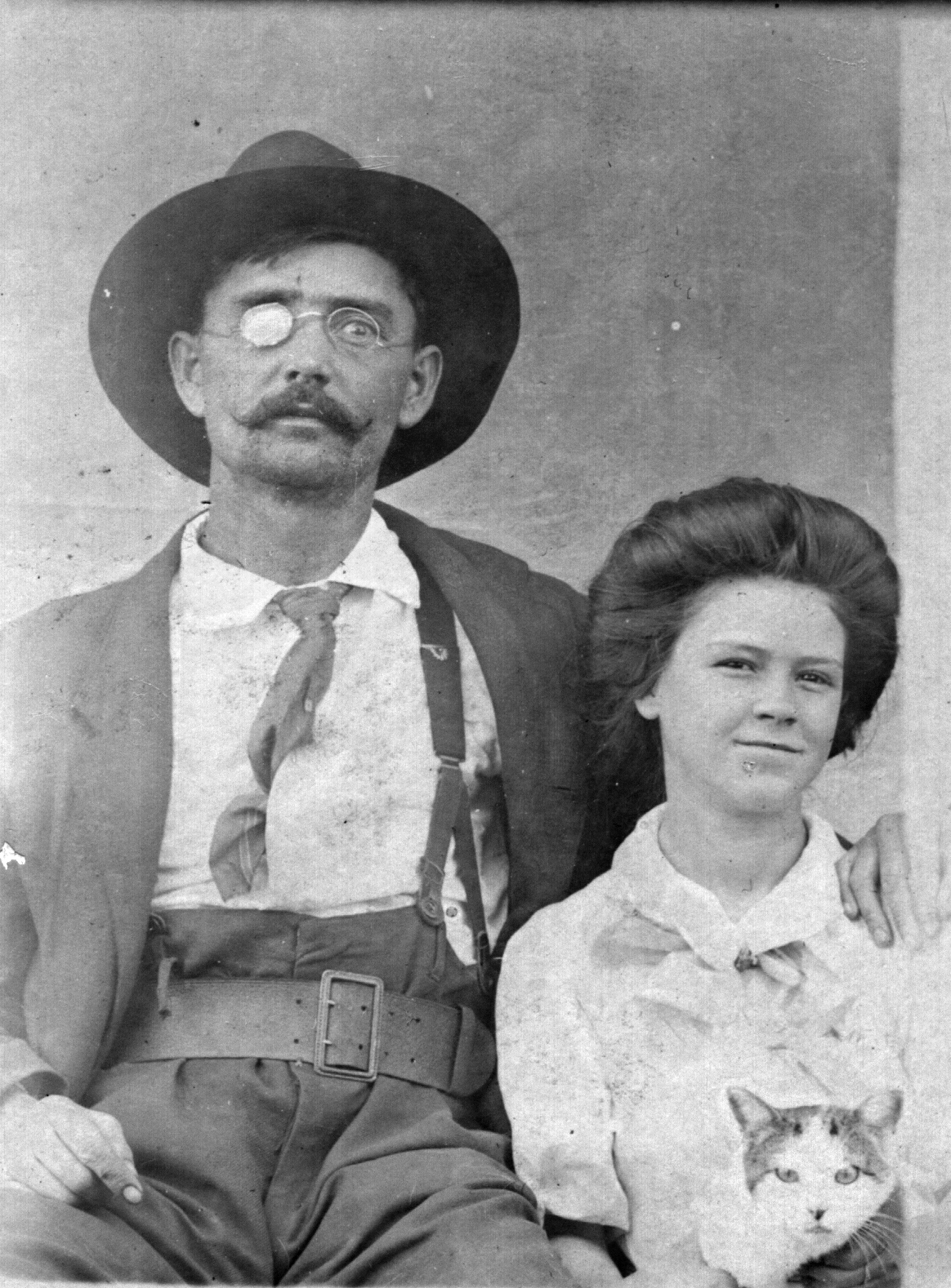My grandfather Benjamin Franklin Taylor and his daughter Camilla and cat.  The photo was taken in Marked Tree, Arkansas in 1909.  Ben had lost his right eye in a hunting accident on the St. Francis River when he was younger.  In this photo he is wearing a gun belt and is carrying a Navy Colt.  Marked Tree was a dangerous logging town and men wore guns for protection.  A year after this photo was taken Camilla, my grandmother, would at the age of 15 marry Wm Robinson, age 31. View full size.