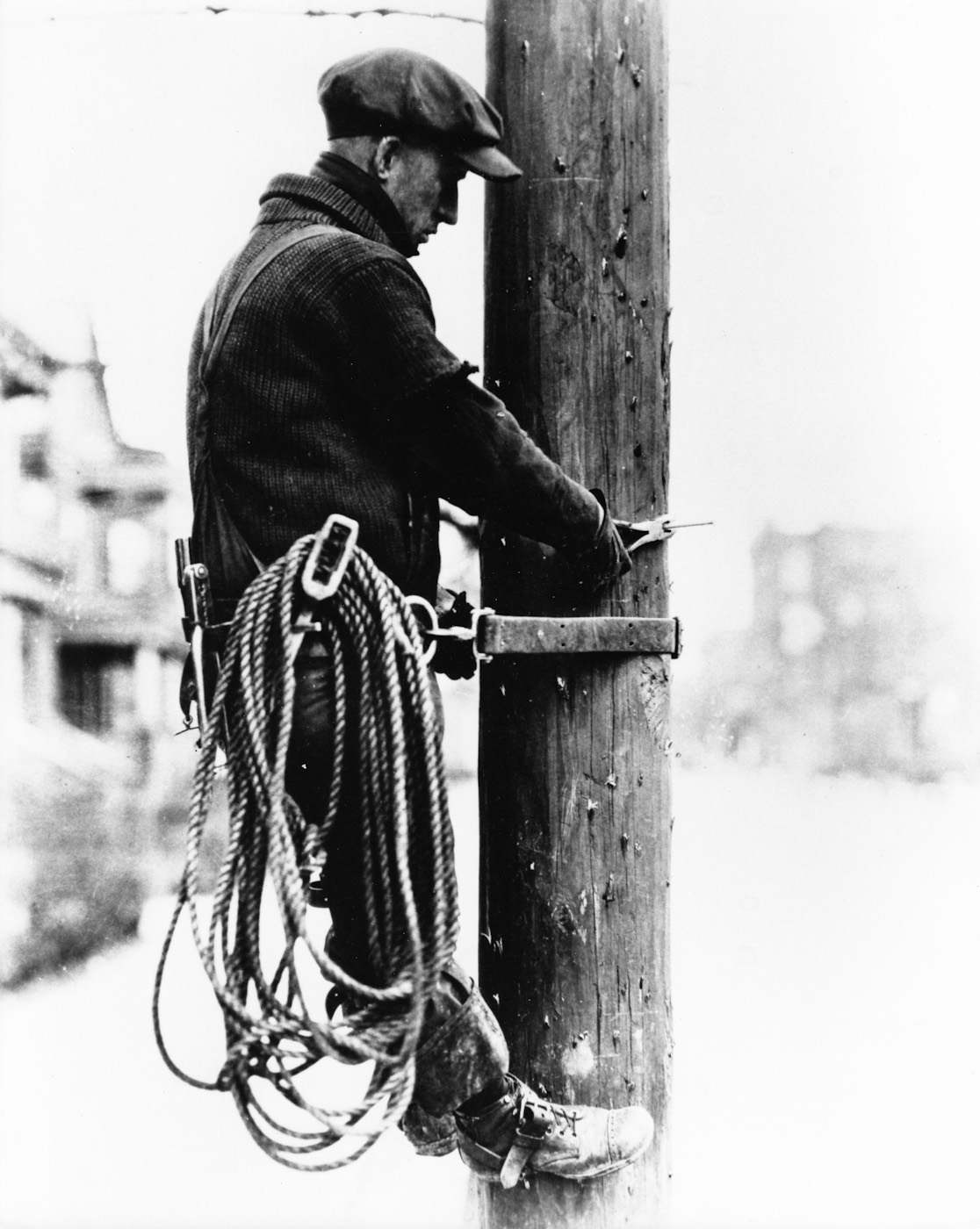 A telephone lineman works on a pole. Location and date unknown. View full size.