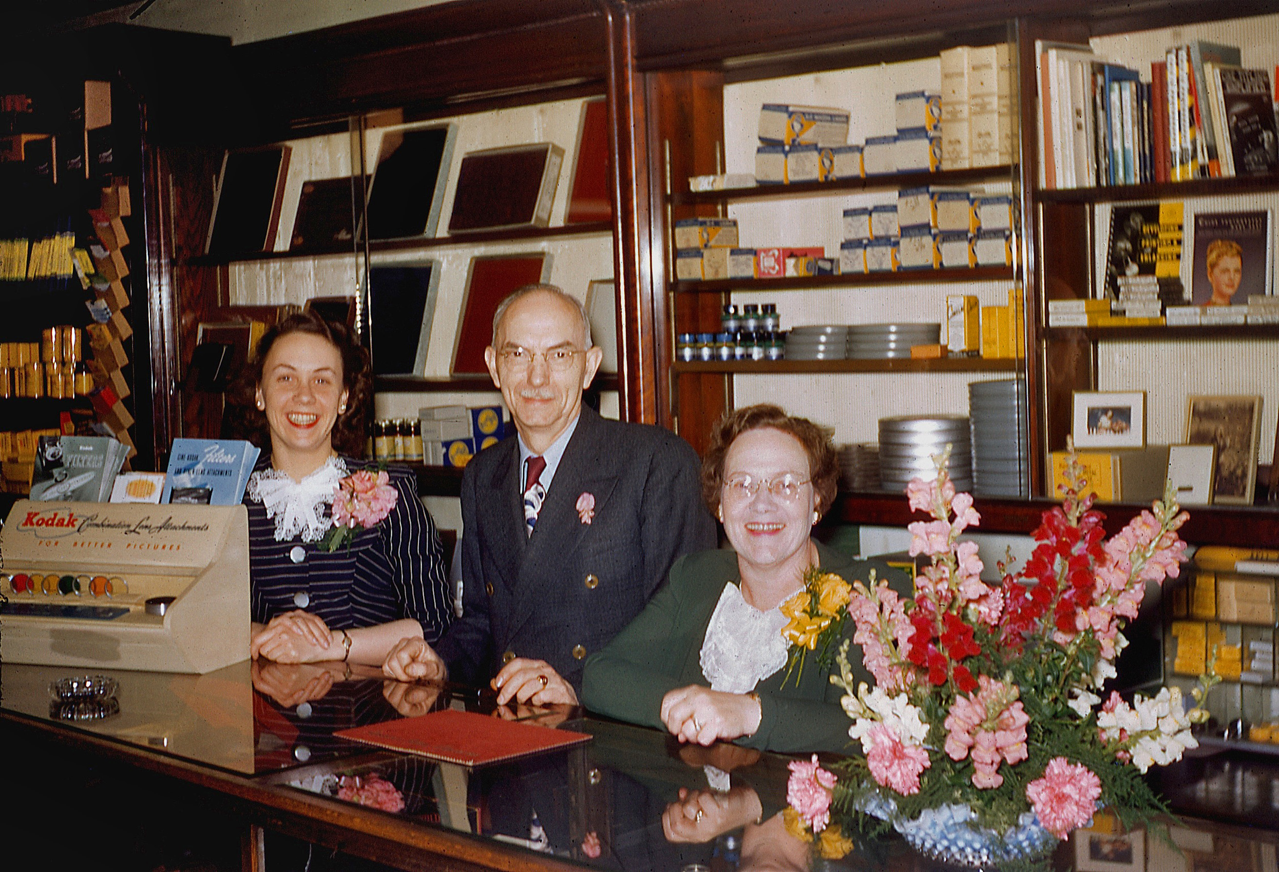 My grandparents Ralph E. and Mildred M. Archer, center and right, in the camera shop they owned and operated from 1929 to 1961 in Titusville, Pennsylvania.  Originally at 104 Exchange Place and then later just around the corner at 113 West Central Avenue. Scan from a 35mm Kodachrome slide. View full size.