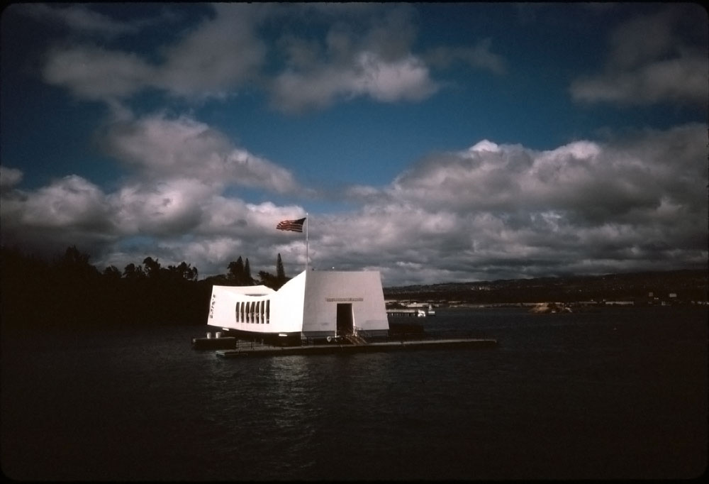 Kodachrome 35mm slide taken in Pearl Harbor by my Aunt Lee in 1984. The slide was not photoshopped other than dust removal. View full size.

The USS Arizona Memorial is a continual manifestation of the original Memorial Day Order:

The 30th day of May, 1868, is designated for the purpose of strewing with flowers, or otherwise decorating the graves of comrades who died in defense of their country during the late rebellion, and whose bodies now lie in almost every city, village and hamlet churchyard in the land. In this observance no form or ceremony is prescribed, but Posts and comrades will, in their own way arrange such fitting services and testimonials of respect as circumstances may permit.

We are organized, Comrades, as our regulations tell us, for the purpose among other things, "of preserving and strengthening those kind and fraternal feelings which have bound together the soldiers sailors and Marines, who united to suppress the late rebellion." What can aid more to assure this result than by cherishing tenderly the memory of our heroic dead? We should guard their graves with sacred vigilance. All that the consecrated wealth and taste of the nation can add to their adornment and security, is but a fitting tribute to the memory of her slain defenders. Let pleasant paths invite the coming and going of reverent visitors and fond mourners. Let no neglect, no ravages of time, testify to the present or to the coming generations that we have forgotten as a people the cost of a free and undivided republic.

If other eyes grow dull and other hinds slack, and other hearts cold in the solemn trust, ours shall keep it well as long as the light and warmth of life remain in us.

Let us, then, at the time appointed, gather around their sacred remains, and garland the passionless mounds above them with choicest flowers of springtime; let us raise above them the dear old flag they saved; let us in this solemn presence renew our pledge to aid and assist those whom they have left among us a sacred charge upon the Nation's gratitude—the soldier's and sailor's widow and orphan.

—General Orders No. 11, 
Grand Army of the Republic Headquarters
http://en.wikipedia.org/wiki/Memorial_Day
