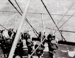 These images show  a Naval burial at sea. Here the Marine Guard fires a rifle salute. The ringing report of the rifles mix with the sound of the ship slicing through the water. View full size.
(ShorpyBlog, Member Gallery)