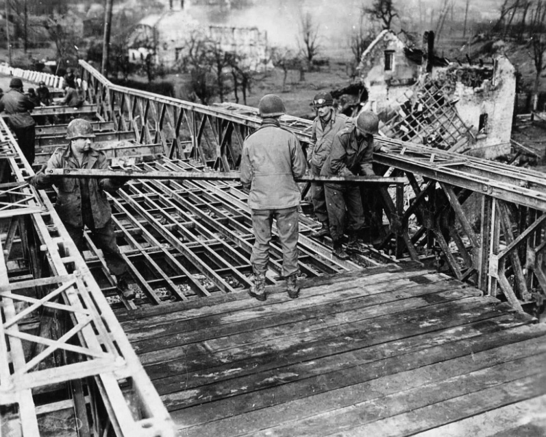 My grandfather's unit building a bridge in Duren, Germany, 1944. Bombed out houses can be seen in the background. View full size.
