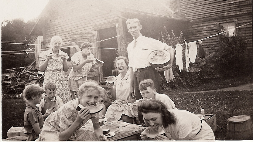 My grandparents, great aunt, aunts and uncles enjoying a watermelon feed.  My grandfather, Charles J. Clarke, was the caretaker of the Clarkson Estate in Potsdam, New York, and he and his family occupied the caretaker's farmhouse on Clarkson Hill. An academic building of Clarkson University now occupies the location. View full size.