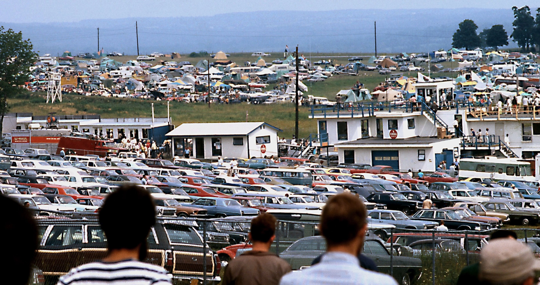 This is part of the parking paddock at Watkins Glen on CanAm weekend, 1970. Lots of American and British/European classics, all collectible today. In the background is the in-field weekend camping area, much of it tents and pickup camper caps then. Was it Watkins Glen or Mosport that the infield was known as "The Swamp" for it's "spirited" nighttime fun? View full size.