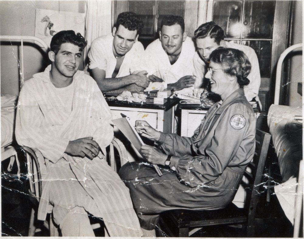 The note on the back says "Mrs. Conant & the boys at the Chelsea Naval Hospital in Chelsea, Mass. Mrs. C. drawing a quick pencil sketch of a wounded Marine or sailor recuperating therein. -  from a letter postmarked Cambridge, Mass, [12]/ 11/44"

Mrs. Conant was a friend of my father's when he attended MIT before and after the war. I think this may be Grace T. Conant, wife of James Bryant Conant, then president of Harvard University. The one photo I can find, taken in 1953 of the Conants, resembles the woman in this photo. Mrs. Conant corresponded with my father during the war, while he was serving with the Canadian Army. View full size.