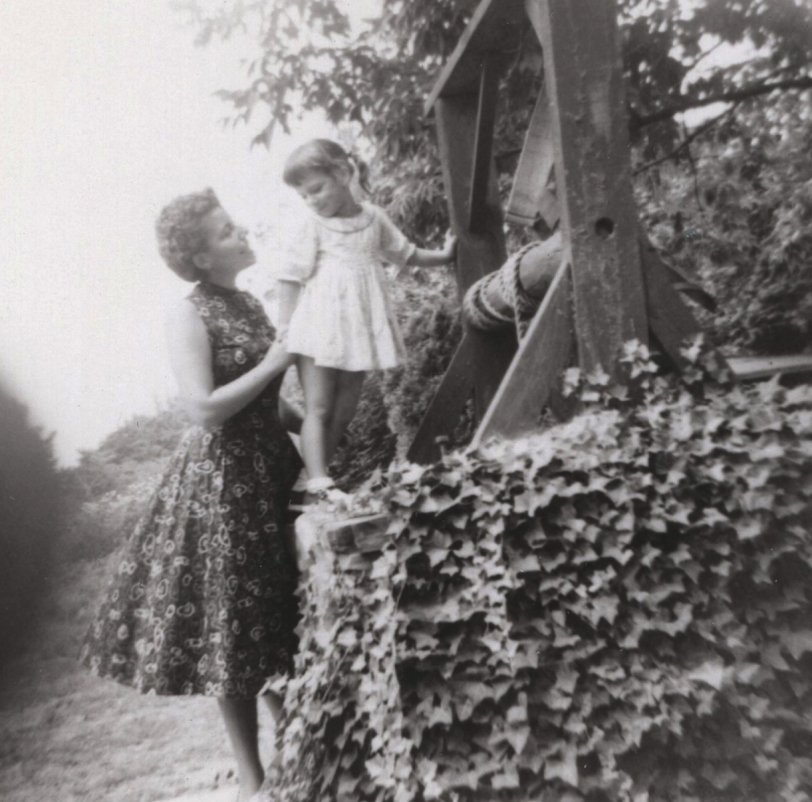 My father took this picture of me and my mother exploring a wishing well that had been overgrown with ivy. She picked me up so I could see the water and bucket that was in the well.
