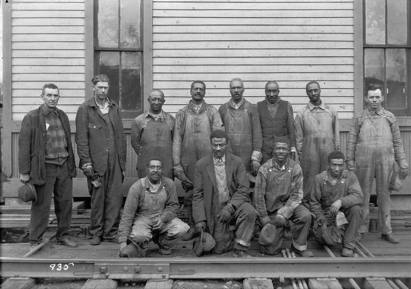 This is a picture of my grandfather Alva Paul LeMay (tall man left of the window) and Chester Duffield (to his left). As the story goes Chester befriended my grandfather, taught him to read and write and got him on at the railroad. Unknown location. View full size.
