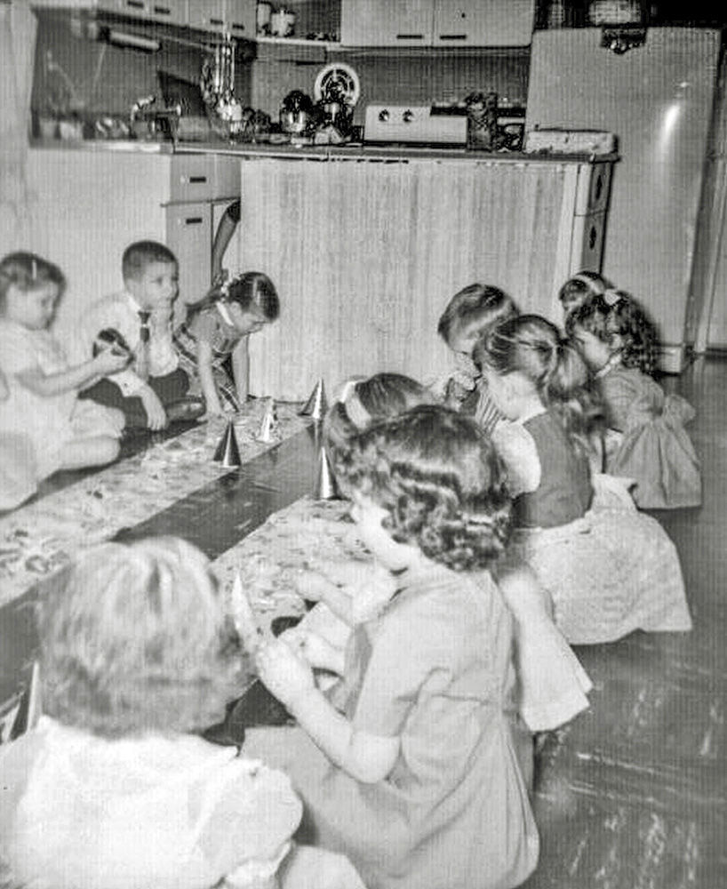 Sometimes parents get very bad ideas. In the case of my fifth birthday party, my mother got this one. She decided that children did not need tables and chairs and bought a roll of shelf paper instead. She took the furniture out of the kitchen and laid two rows of paper on the kitchen floor. We all had to sit on the floor to eat the cake and ice cream with the shelf paper serving as a festive “table cloth.” She thought it was brilliant. I thought it was a nightmare. 

After I decided to post this picture to Shorpy, and had scanned it, I asked my mother why she did that. She continued to boast what a great idea it had been. But she did admit that her inspiration was that I had invited more children than we had tables and chairs for. Either we bought more chairs by the time I turned six, or I invited fewer guests, because she did not do this party on the kitchen floor again.