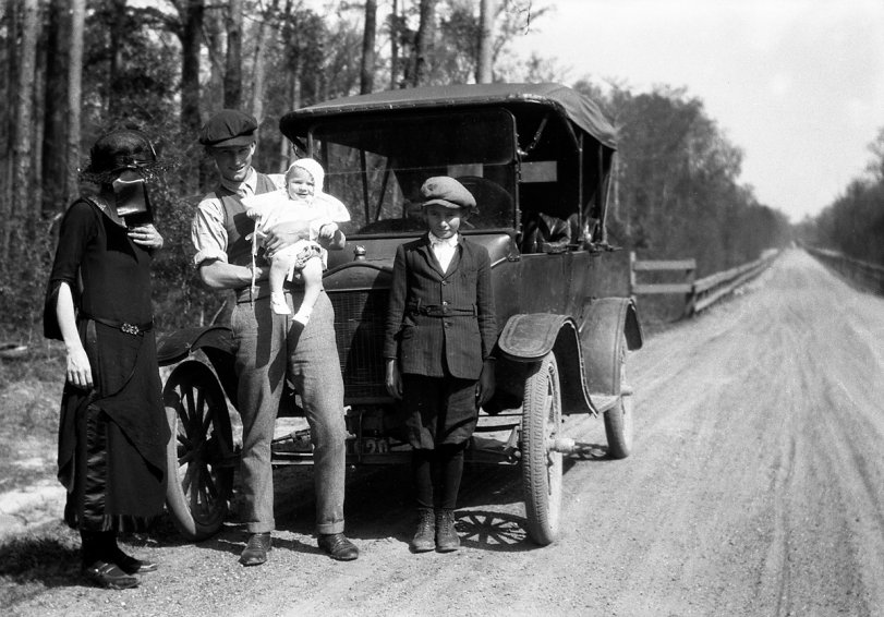 This photo was taken in early 1923 by my grandfather, J. H. Bourg. The location is on the old Oakdale Road between Elizabeth and Oakdale, Louisiana, close to the Calcasieu River. The girl whose face is hidden by the hat ribbon is my grandmother, Eva Sigler Bourg. Her brothers Clint and Lenox are along for the ride.  Clint is holding his nephew Gerald Bourg. View full size.
