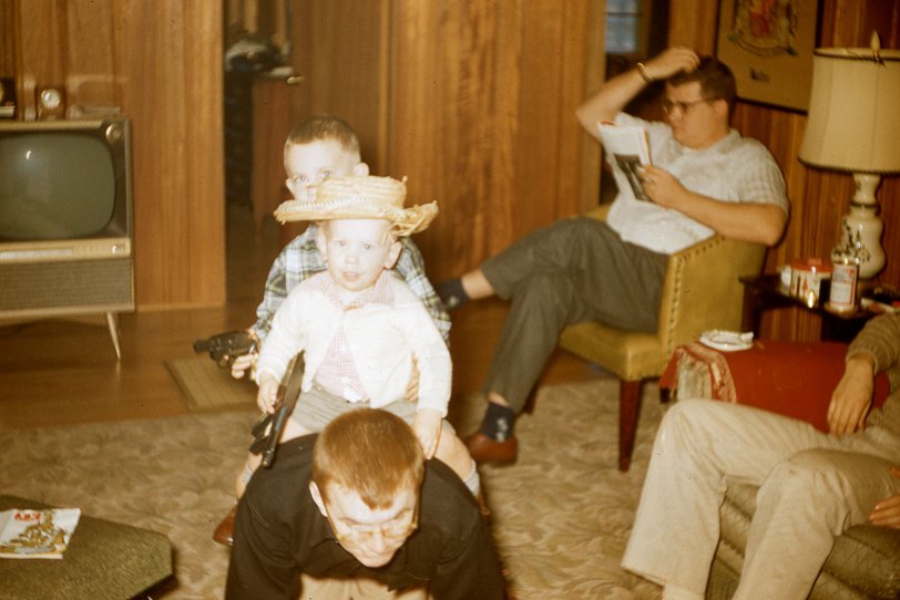 My brother (front) and I are "horseback riding" our father at Christmastime 1958, in Connecticut. We are armed with decidedly urban-looking weapons despite my brother's rustic cowboy hat. One of my uncles (seated) may have been consulting the TV Guide in the lower right corner, for the week of December 20-26, 1958, to decide what to watch on the gigantic--for its time--television set. 
Photograph by my grandfather, Edward Butler, whose work has previously been featured on Shorpy. Scanned February 2021 from a 35mm Kodachrome slide. 
