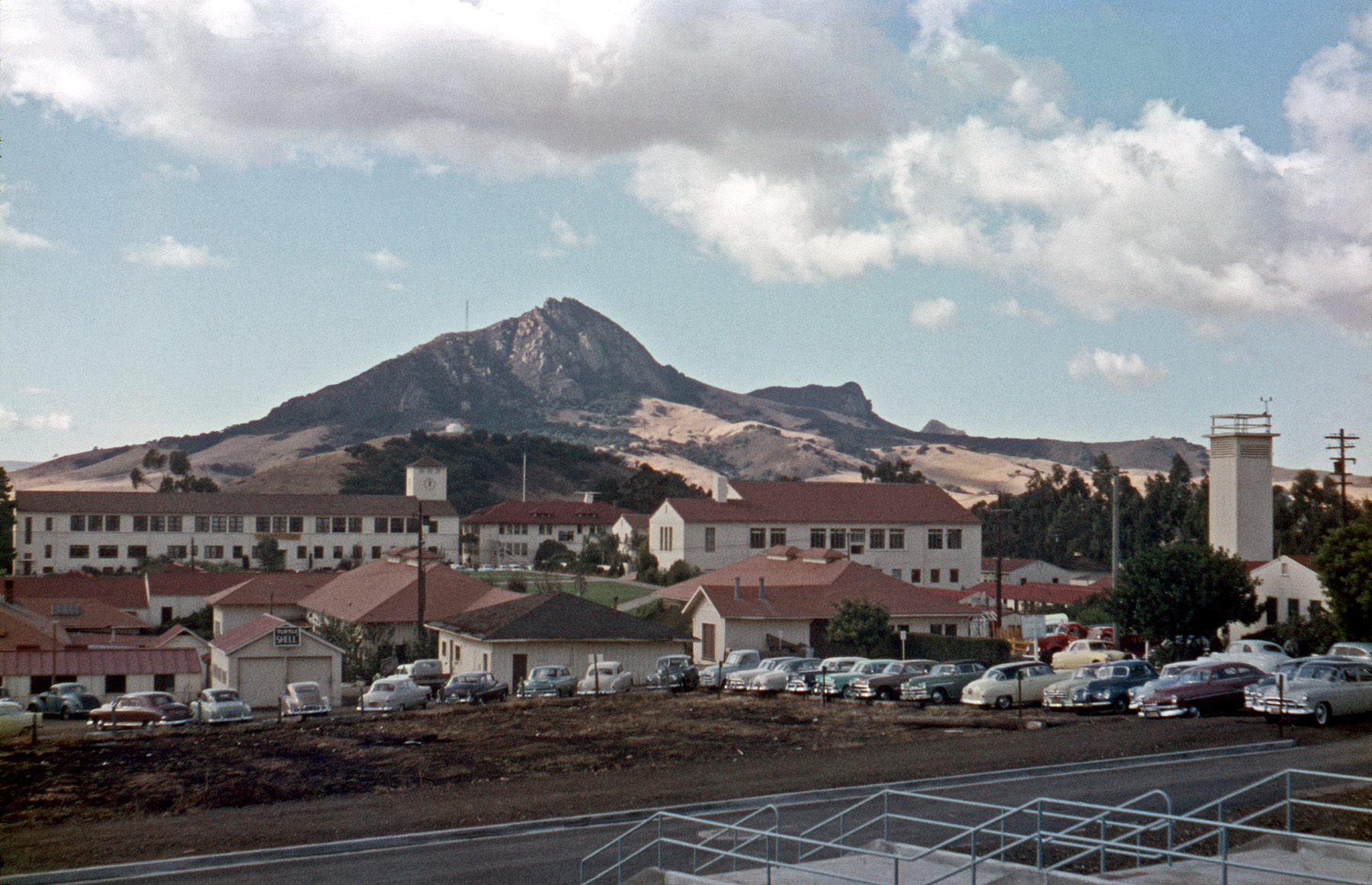 Not as many this time, but a couple of obsolete models, such as the first design of a Kaiser or Frazer, and an early Nash Rambler. Also a good representation of vintage Cal Poly color scheme. Same period, around 1956, this time on Anscochrome. View full size.