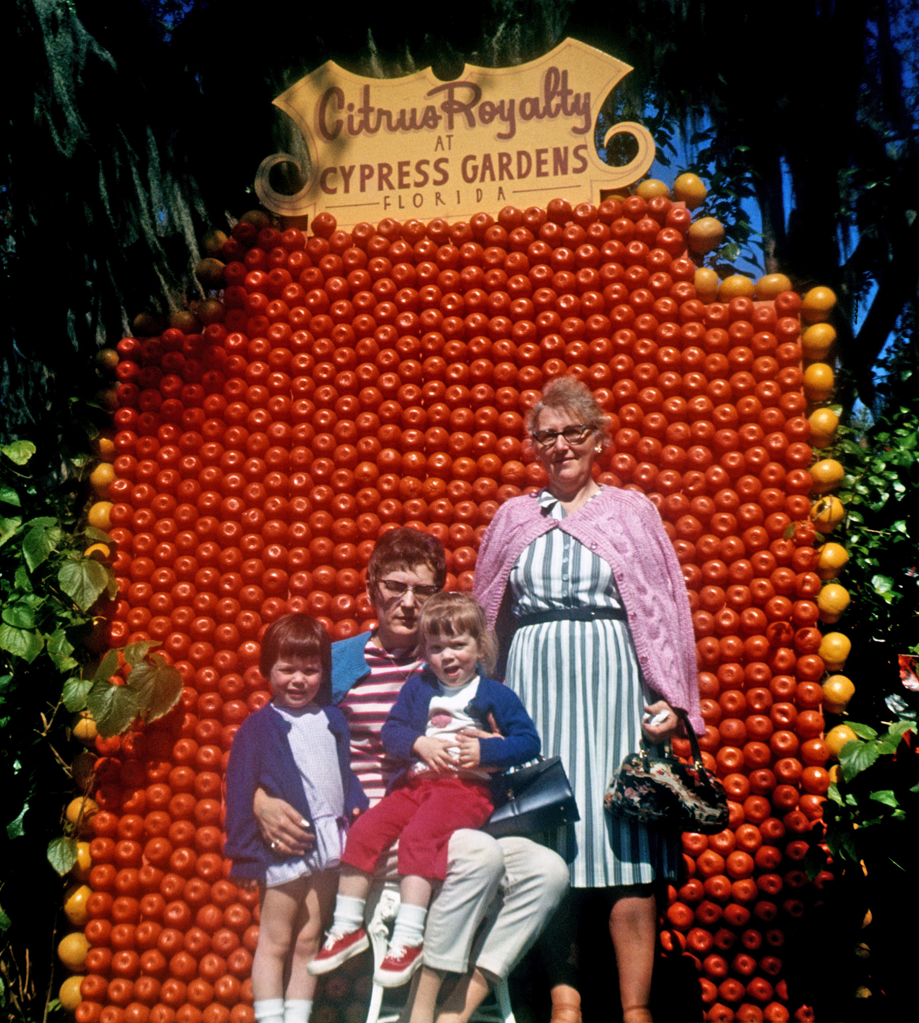 From a friend's collection of her family's slides I'm scanning for her. She's the little girl on the right, along with her older sister (previously seen here on Shorpy), and their aunt and grandmother. Shot on 126 Ektachrome. Obviously this family was big into fruit. View full size.