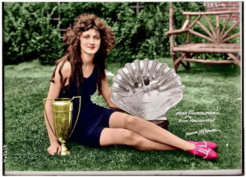 I saw this photo of 1924's Miss Philadelphia/Miss America Ruth Malcolmson on Shorpy and just had to see what it looked like colorized. I have to admit that one part of the photo gave me trouble. In the original there was the side of a house with all sorts of little items in the upper right corner. I simply couldn't identify everything to determine what color the items should be so I 'grew' some more bushes up to the brickwork.
Anyway, hope someone enjoys this as much as I did working on it the past 2-3 weeks. View full size.
