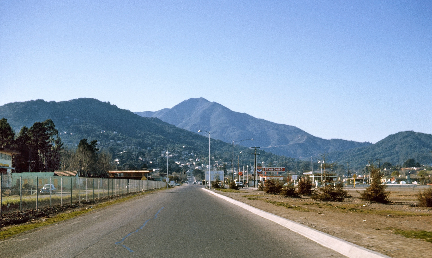 The southbound on-ramp to U.S. 101 in Corte Madera, California, in a Kodachrome slide I shot through the back window of our 1956 Rambler station wagon in January 1963. Corte Madera is the "twin city" of my home town, Idyllic™ Larkspur. Rising up in the distance is Marin County's iconic symbol, Mount Tamalpais. Closer and to the left, Corte Madera's "Christmas Tree Hill" is so-named from the practice, in days of yore, of homeowners banding together to illuminate their houses to produce an outline of a Christmas tree when viewed from the distance. To the right, Larkspur's Little and Big King Mountains. Yes, we call hills "mountains" in Marin County. Fortunately, they're protected from development by open-space regulations, and Mt. Tam by state park and Marin Municipal Water District ownership. View full size.