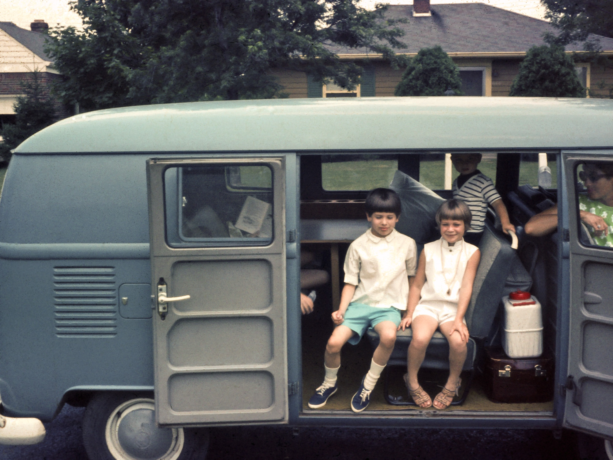 Indianapolis, Indiana, 1969: My sister Anne, age 9, is on the left in the turquoise shorts.  She and her classmate Anne B. are sitting in the B's family VW van ready to leave for their first trip to CYO Camp Rancho Fromasa (near Nashville, IN).

Anne B. appears (literally) not to be a happy camper. In fact my sister said that her classmate stayed unhappy the whole time they were at camp.

While cleaning up the image I realized that the body lying in the back seat reading a book is likely Anne B's older brother, and my classmate, Mark.

35mm Slide film image taken by my father, digitized by my brother and tidied up by me. View full size.