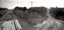 Railroad crossing near McCook, Nebraska, around 1932. View full size.
I Give Up!Just past the crossing, on either side of the tracks are wooden things supported by posts with some sort of mat running between them between the tracks. What the heck is that for?
[Cattle guard. - Dave]
(ShorpyBlog, Member Gallery, Railroads)
