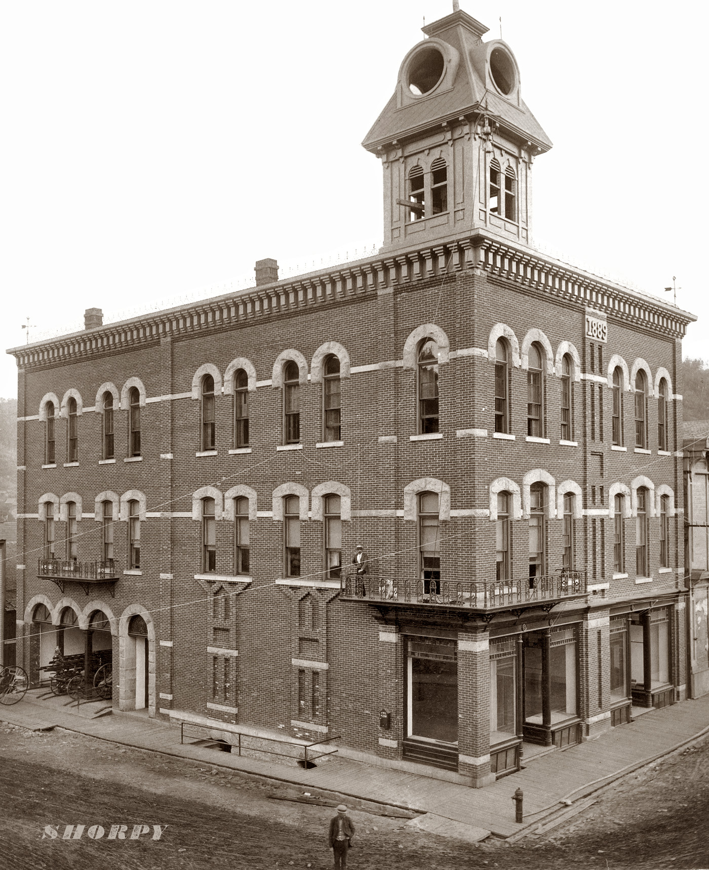 Deadwood City Hall in 1890 shortly after its completion. Note fire wagons in garage, fire alarm and fire hydrant. The building burned to the ground in 1952. Those are electric arc lights mounted up near the belfry. View full size. Photograph by John C.H. Grabill.