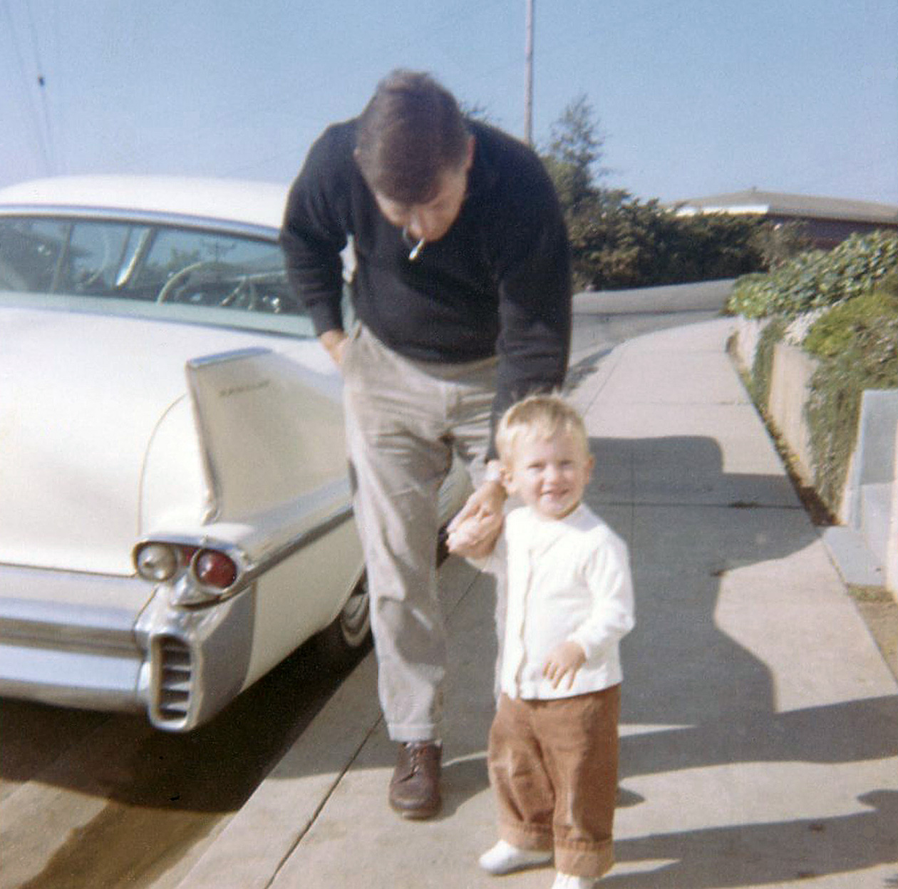 Another photo from 1964 with Gramp's '58 Cadillac (previously seen here) parked at the curb.  I thought the Cad had curb feelers but I don't see evidence of them in this photo.  That's me and my dad posing for Gramp's camera.  I would have been two and dad would have been 34.  Looks like he's smoking but that's actually the zipper on his sweater reflecting the sun. View full size.