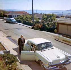 My mother's parents are seen here getting ready to drive home to Sacramento after a weekend visit in 1964. We lived in the San Francisco East Bay hills for over 20 years and this house had a wonderful panoramic view of the Bay.  San Francisco can be seen in the left distance as can the Golden Gate Bridge in the distance at right.  Grandpa's car was a 1958 Cadillac - he was a Cadillac man for years. The car down the street is a c.1954 Nash Ambassador.  As a toddler I would stand out on our deck and stare out at that incredible view. View full size.
Very evocativeEspecially since I lived in the East Bay as a child and by 1964 I was living in Sacramento. One thing that struck me though, was the idea that this gentleman, after a weekend visit and prior to a long drive, would be wearing a suit and tie. Still dressed for church, perhaps?
LocationShorpy,  this appears to be El Cerrito, fairly high up on the hill.
WonderfulLove the picture. Thanks so much for sharing.
What a viewWhat a wonderful place to grow up in!!
Judicious commentIf I didn't know better, I'd think your granddad was U.S. Supreme Court Chief Justice (and former California governor) Earl Warren.
1958: Swan song for Harley Earl58 was the last model year GM products were designed under the direction of ‘Misterl.’ Earl had made it clear he wanted the 59s to be more of the 58s. While he was sunning himself on the French Riviera in 1956, GM design staff got a peek at the 57 Chrysler product line (Virgil Exner’s ‘forward look’) at the Warren, Michigan assembly plant. Panic set in and Bill Mitchell, minding the GM design department in Earl’s absence, told staff in all five divisions to disregard Earl’s wishes and to start from scratch with the 59 products. Upon his return to Detroit Earl quietly acquiesced to the changes made in his absence, given that Mitchell had secured the support of senior GM management. The posted Caddy has Harley Earl written all over it---in capital letters. Every feature is massive, bold and in-your-face pretentiousness with lots of chrome. I love it.    
Fortunate Son!How fortunate to have experienced such a spectacular vista while growing-up. The beauty of that perspective must have inspired you. 
WhitewallsIn my opinion, Grandpa parked dangerously close to the sidewalk, and those whitewall tires are in danger. I would advise some curb feelers.
Dream CarI.WANT.THIS.CAR.
Suit and tie?Well into the 70's, when my parents would come for a visit, Dad would always be dressed exactly this way. Seemed perfectly natural seeing the photo.
Thanks for the commentsYes, it was the extreme north end of El Cerrito, maybe even East Richmond Heights.  I would assume that we had gone to church that morning and that explains the dress code.  I have at least one other photo of the Cadillac parked there and I think it did have curb feelers.  One can imagine that the men like my grandfather, men of the whitewall era, were expert at curbside parking without scuffing their car's whitewalls.  Gramp's previous car was a '55-'56 Cadillac Sedan DeVille.  My mother took the photo from the end of the deck that went off of the north end of the house.  I used to stand up there, on a picnic table bench that my mother pushed up to that end of the deck, and stare out at that view when I was a toddler--no doubt why I love a good view to this day.  Yes, Gramp looked like Earl Warren!
[Here's the other photo. - tterrace]
(ShorpyBlog, Member Gallery)